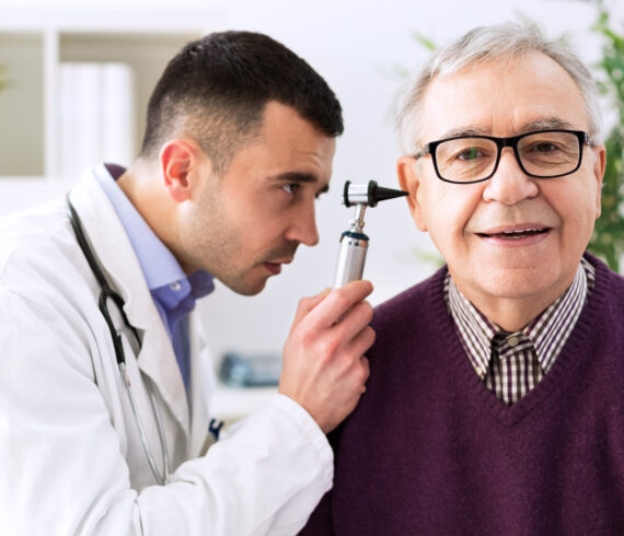 Doctor holding otoscope and examining patient ear