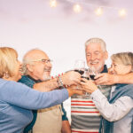 Happy Senior Friends Cheering And Toasting With Red Wine On Terr